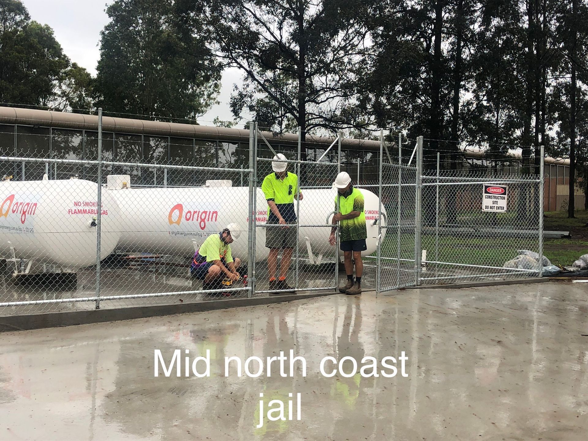 Three workers install a fence near white gas tanks at a jail on the mid north coast — Fencer Steve In Temagog, NSW