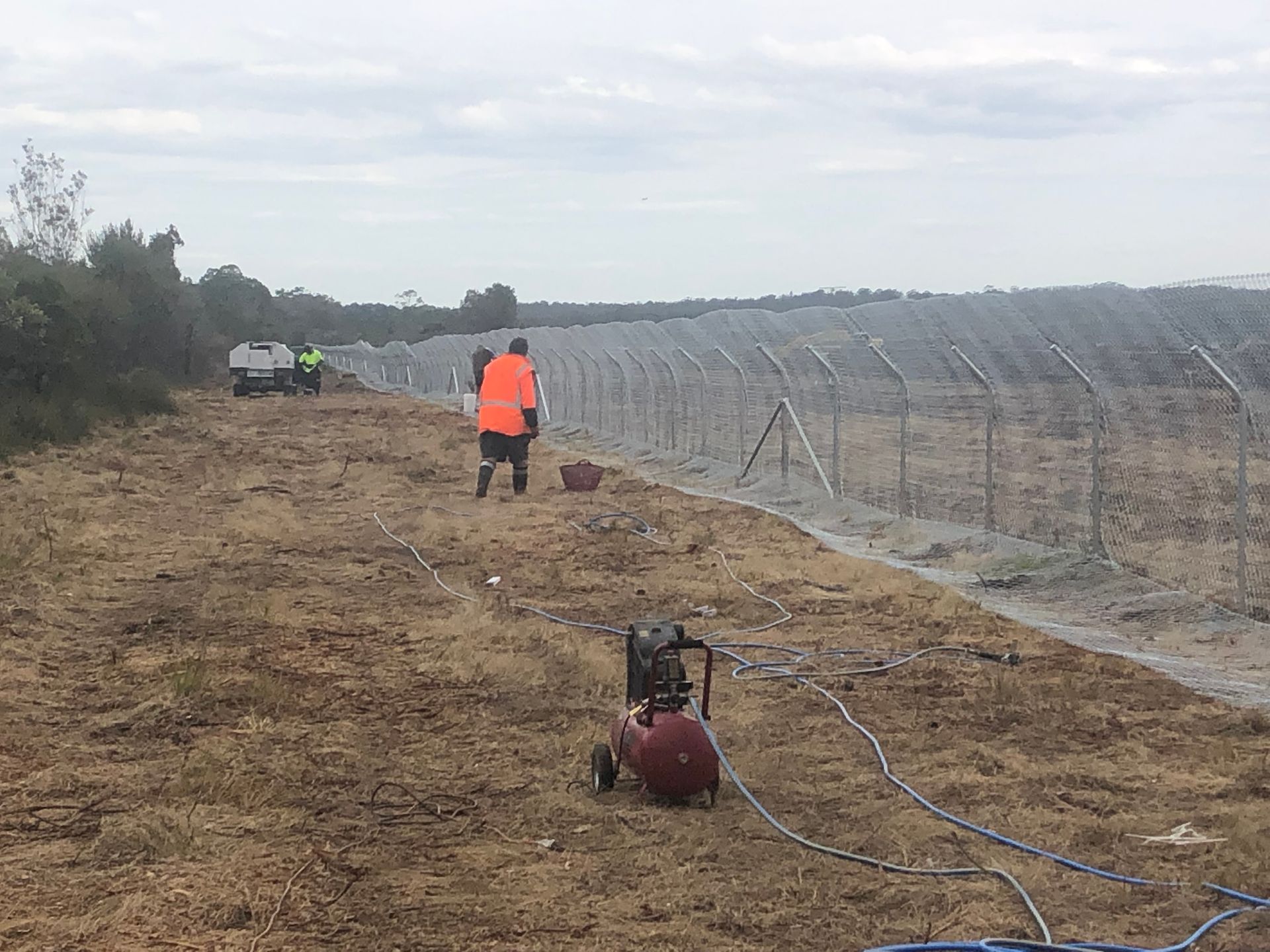 Workers Near a Fence, With Equipment in a Field Under a Cloudy Sky — Fencer Steve In South West Rocks, NSW