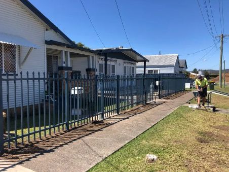 Blue Metal Fence Along a Sidewalk in Front of White Houses — Fencer Steve In Crescent Head, NSW