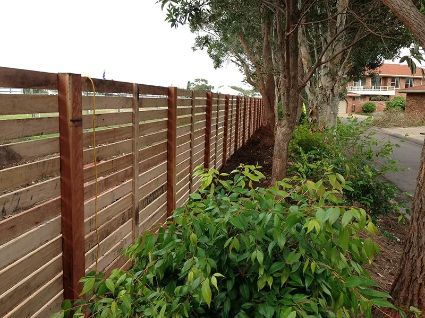 Wooden Horizontal Slat Fence Bordering a Grassy Area — Fencer Steve In Laurieton, NSW