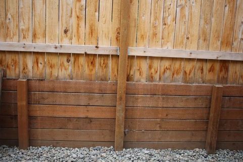 Wooden Fence With a Retaining Wall Made of Horizontal Boards, Gravel Base — Fencer Steve In Kempsey, NSW