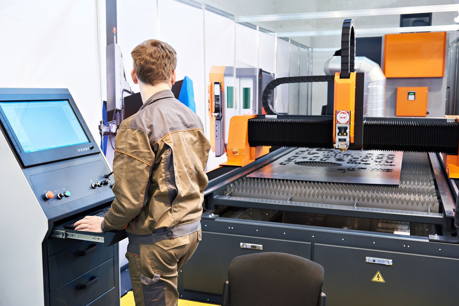 A rear view of a technician in a laser-cutting complex for metal.