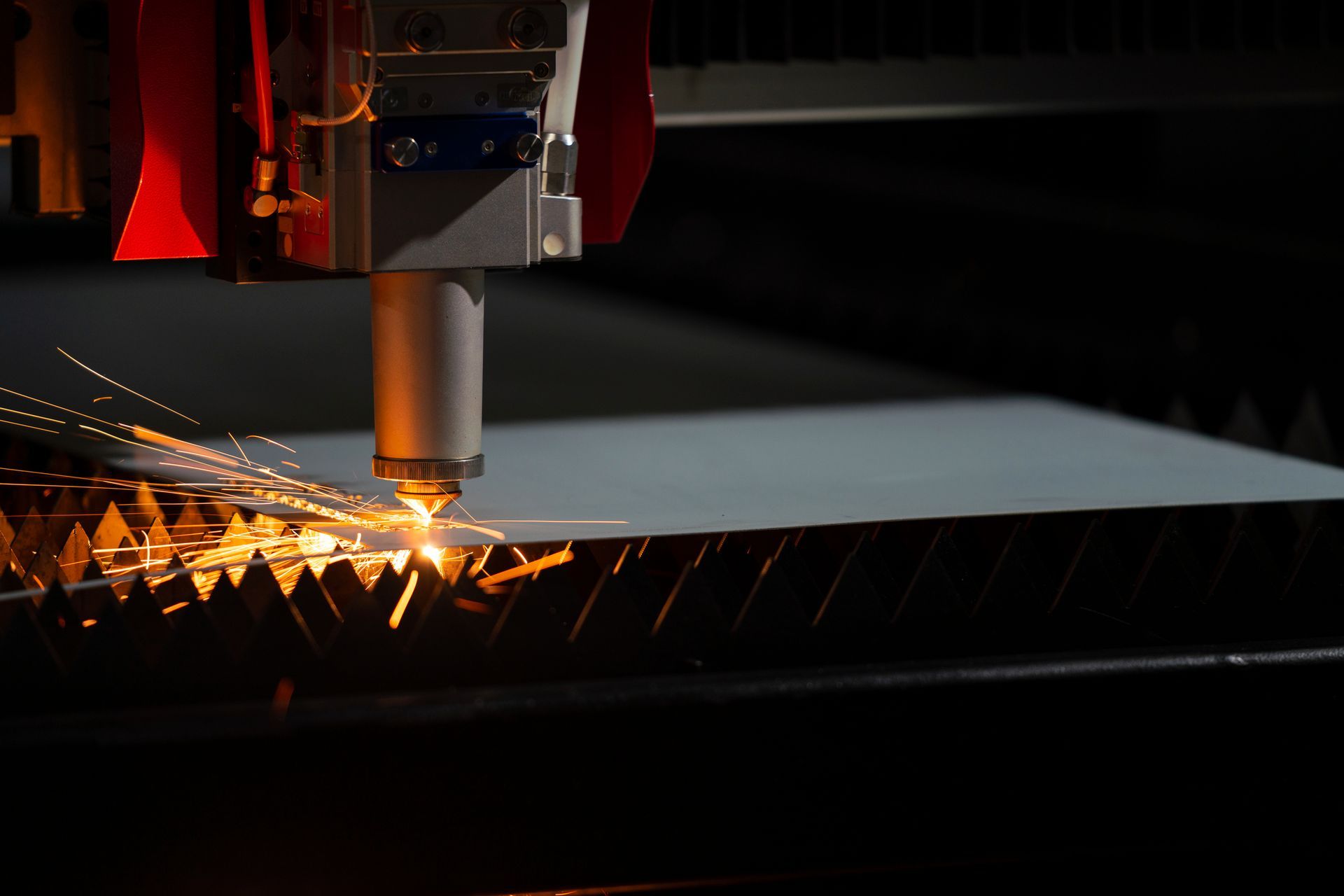Laser cutting machine emitting sparks while cutting metal sheet.