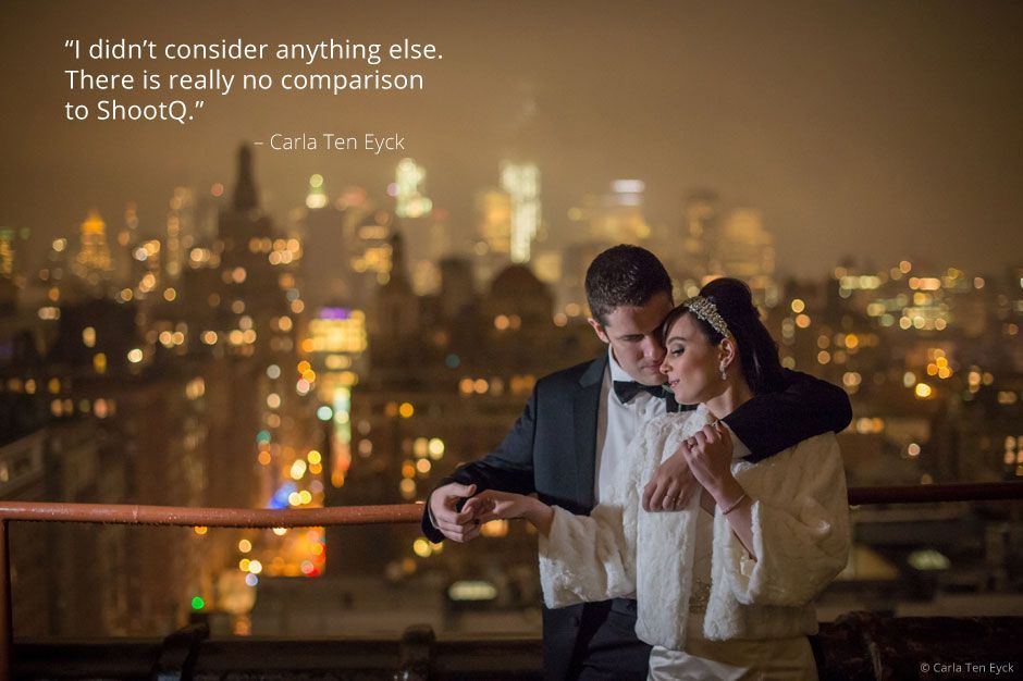A bride and groom are standing next to each other in front of a city skyline at night.