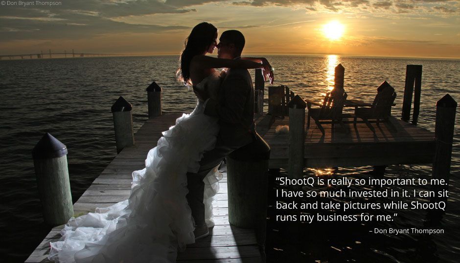 A bride and groom are kissing on a dock at sunset