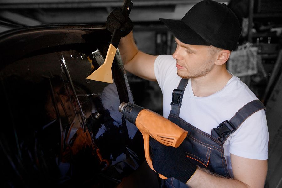 a man in a black hat and overalls waxing a car