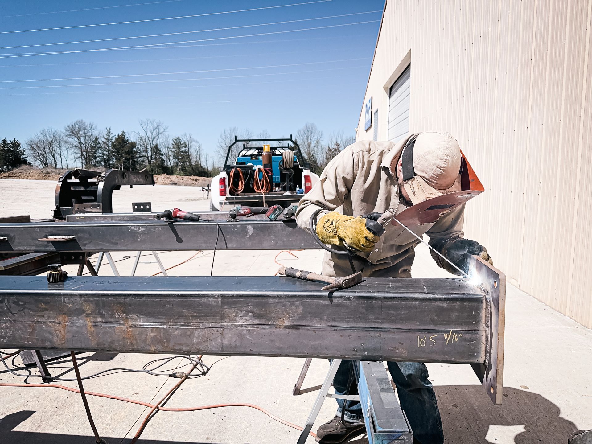 A Welder From Mid-Missouri's Merit Welding Handling a Metal Bar Outdoors. Call for Mobile Welding!