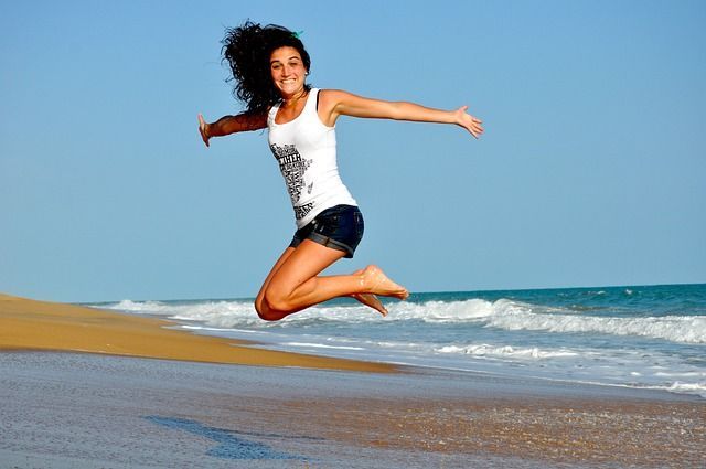 Une femme saute en l'air sur la plage