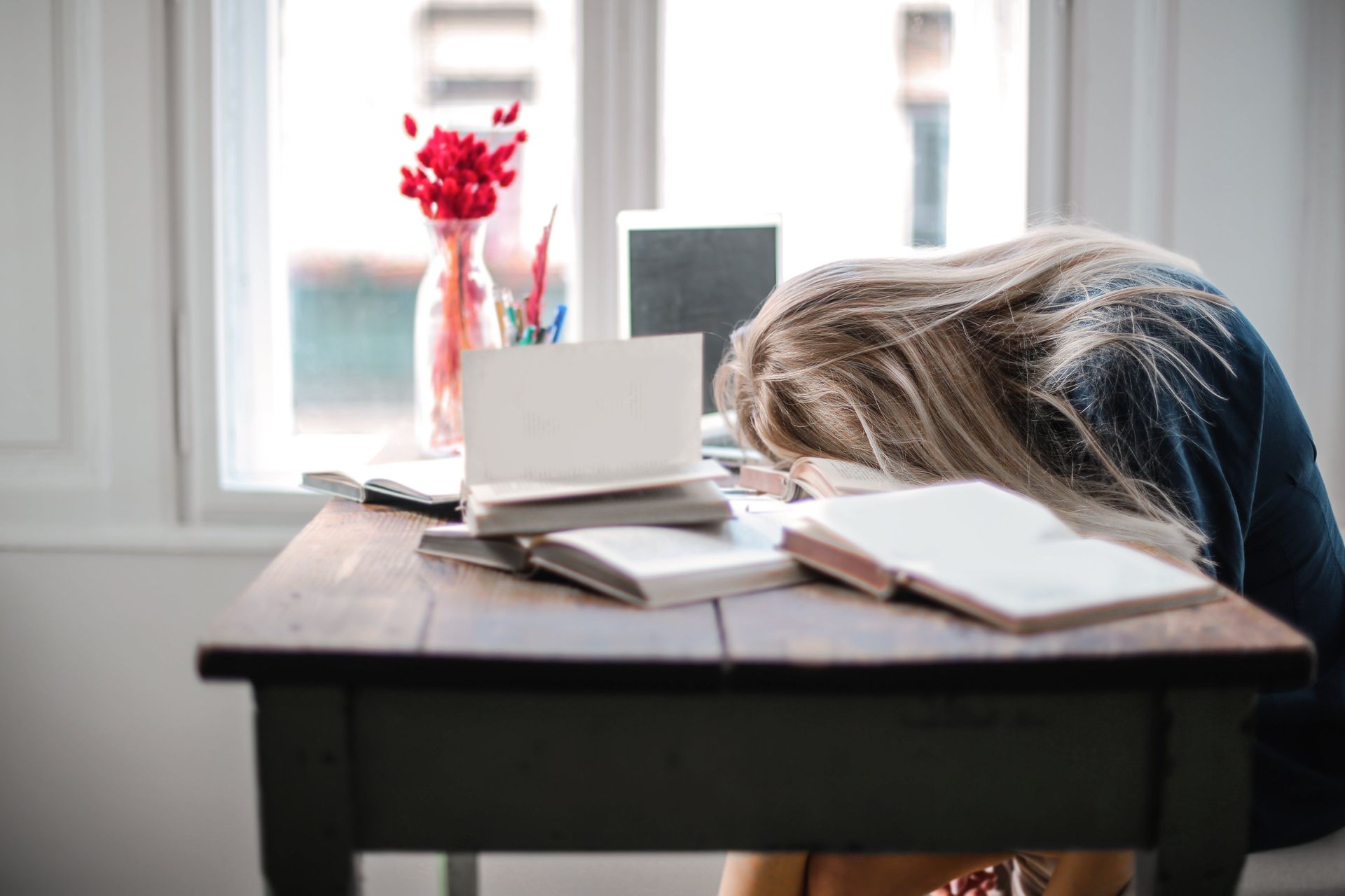 Une femme dort à un bureau avec sa tête sur le bureau.