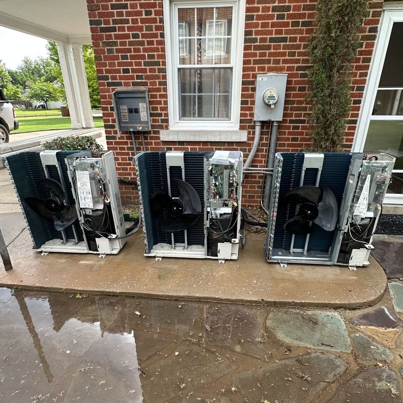 Three Daikin HVAC units lined up against a red brick building with stone walkway.