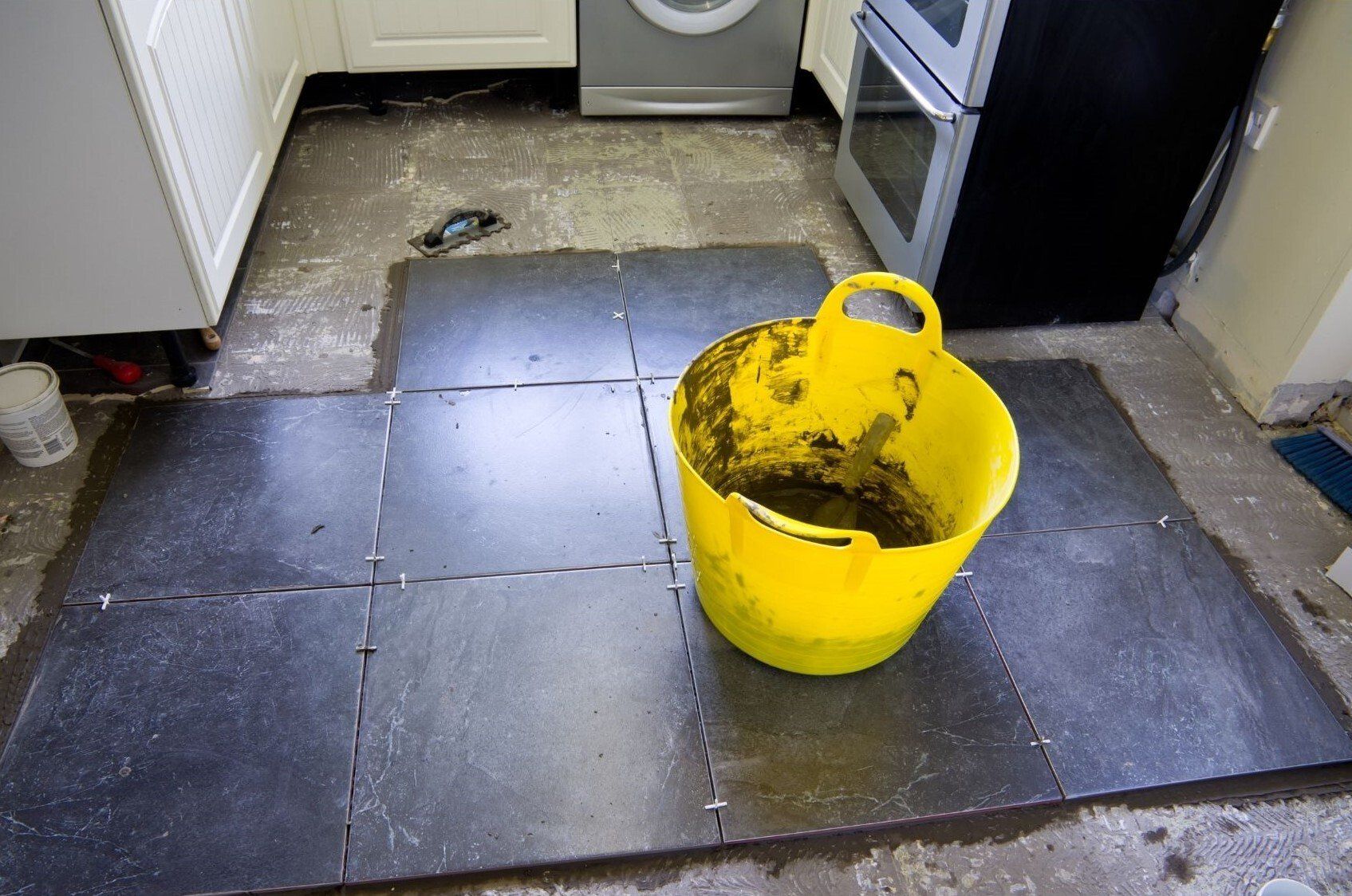 Langley Handyman installing new black tile flooring in kitchen