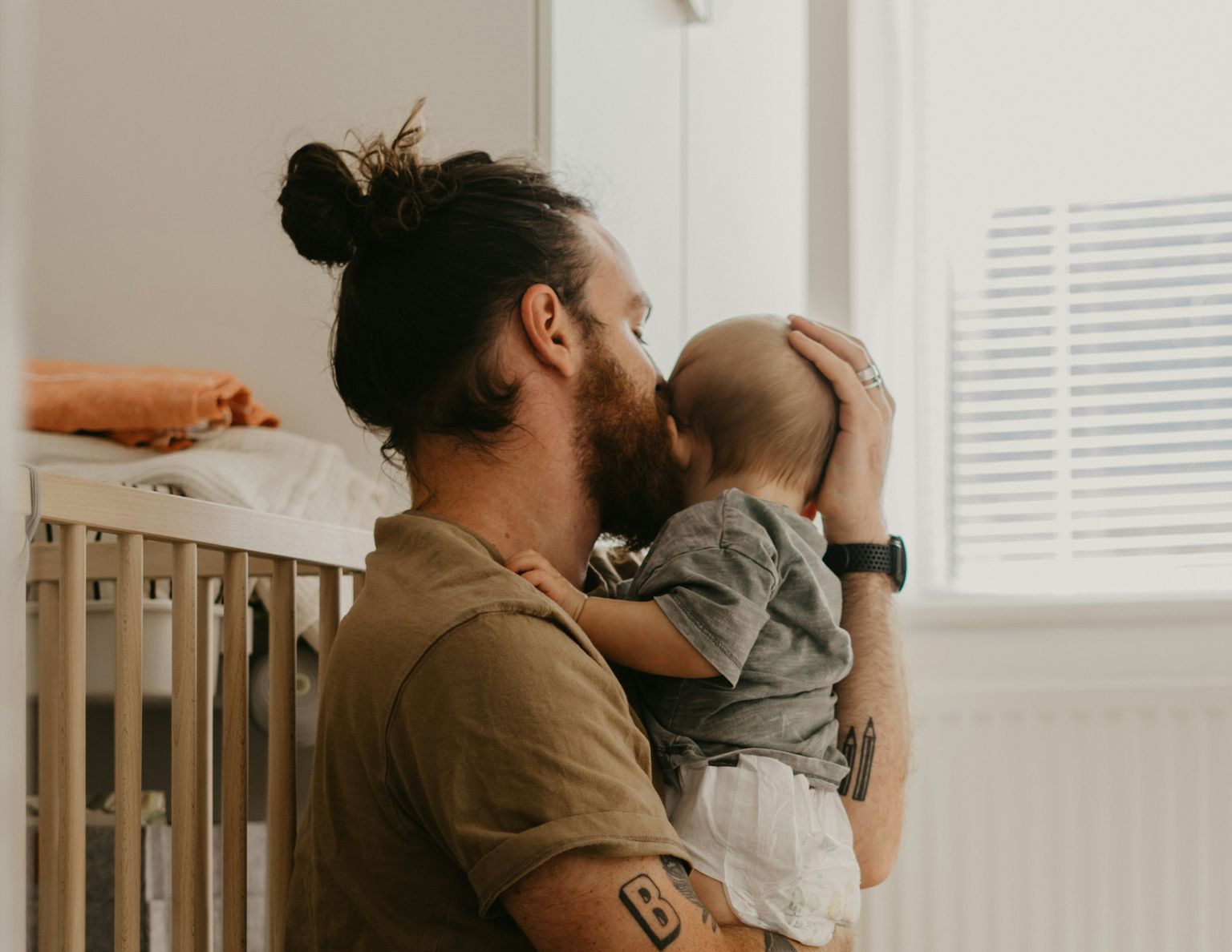 A man with a beard is holding a baby in his arms.