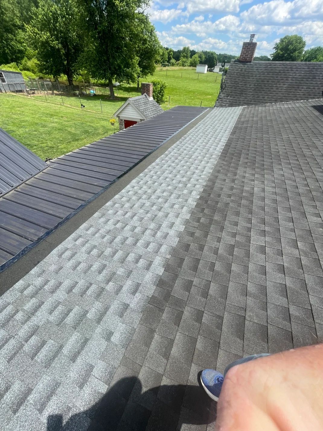 Close-up of a roof with a section of new light gray shingles next to older dark gray shingles.