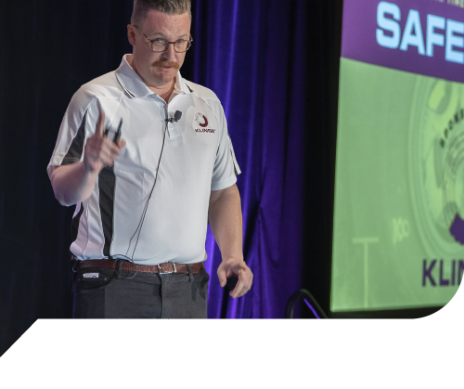A man giving a presentation in front of a screen that says safe