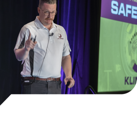 A man giving a presentation in front of a screen that says safe