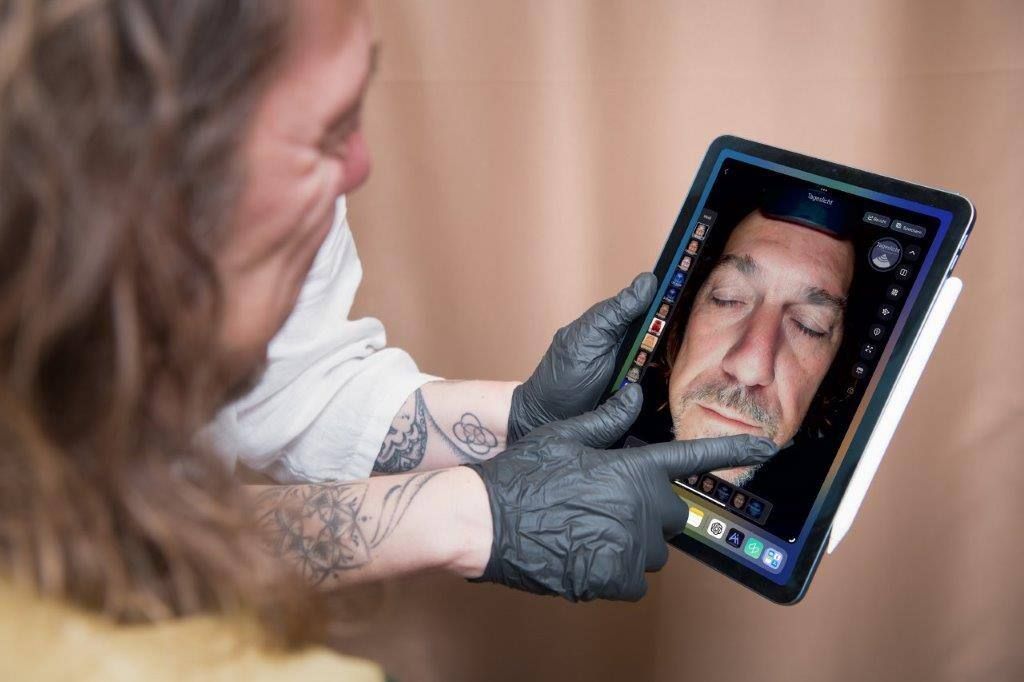 Ein Mann hält ein Tablet mit dem Bild eines Mannes darauf.