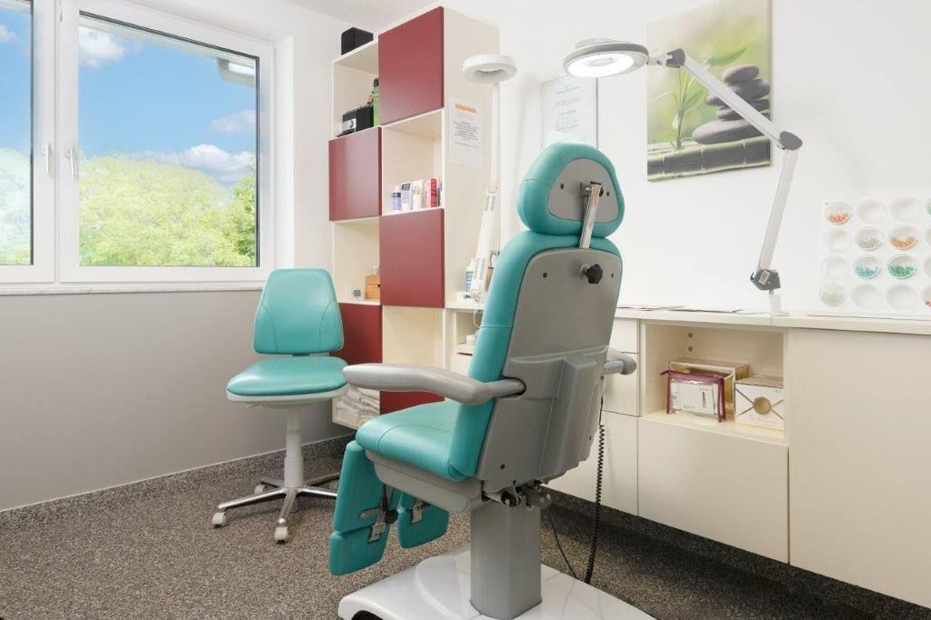 Ein Zahnarztstuhl steht in einem Raum neben einem Fenster.