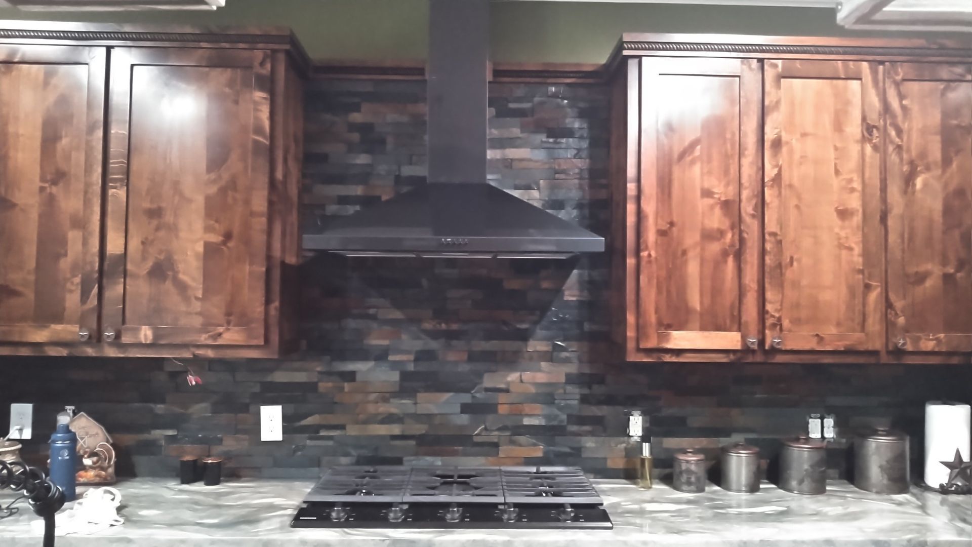 A kitchen with gray cabinets , a stove , and a sink.