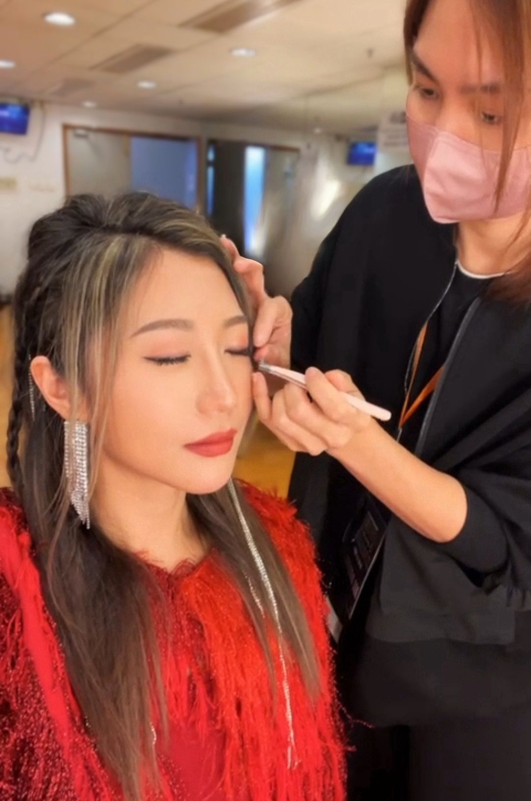 一位女士正在由一位戴著口罩的女士化妝。