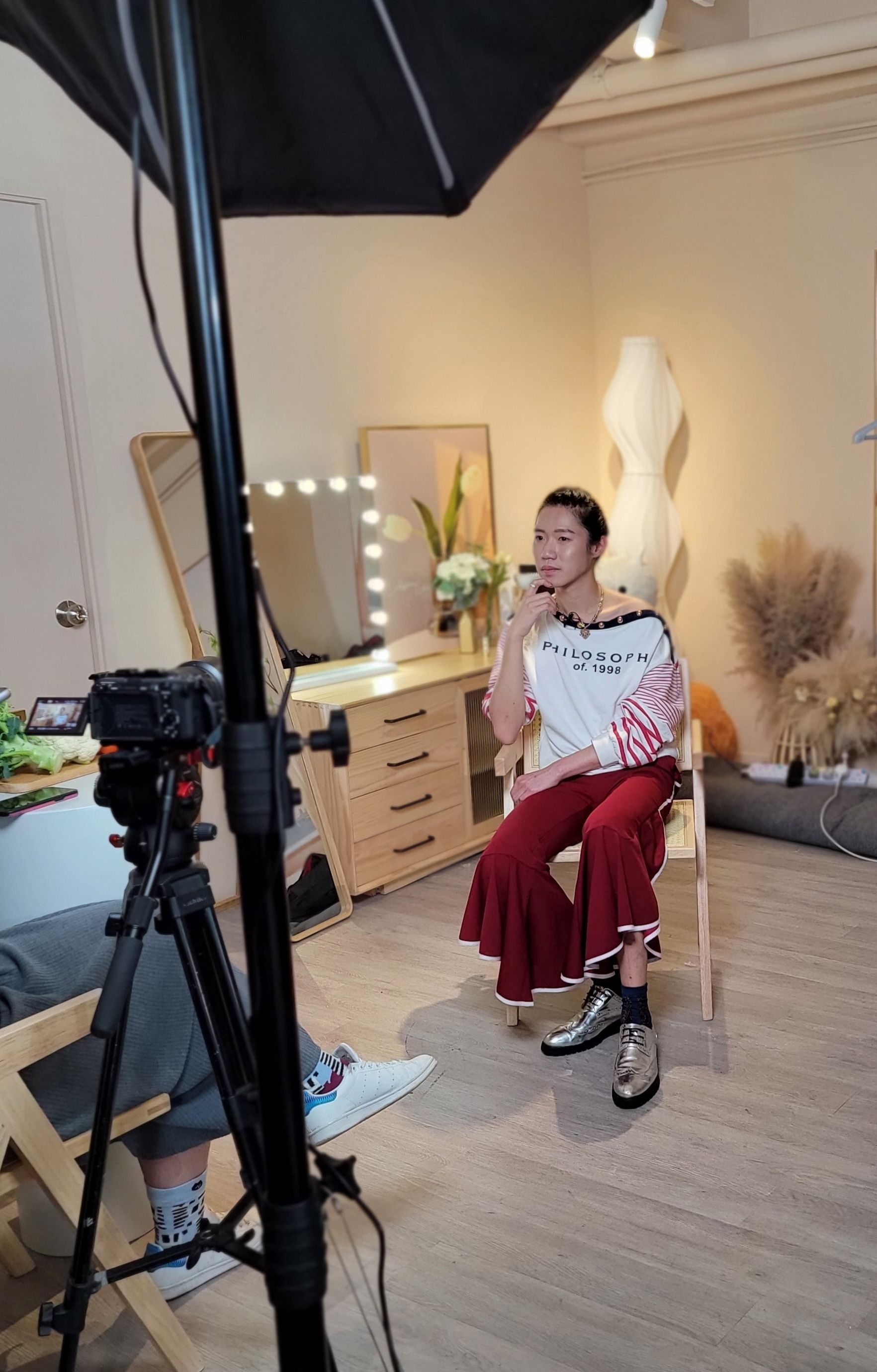 一個女人坐在房間裡攝影機前的椅子上。