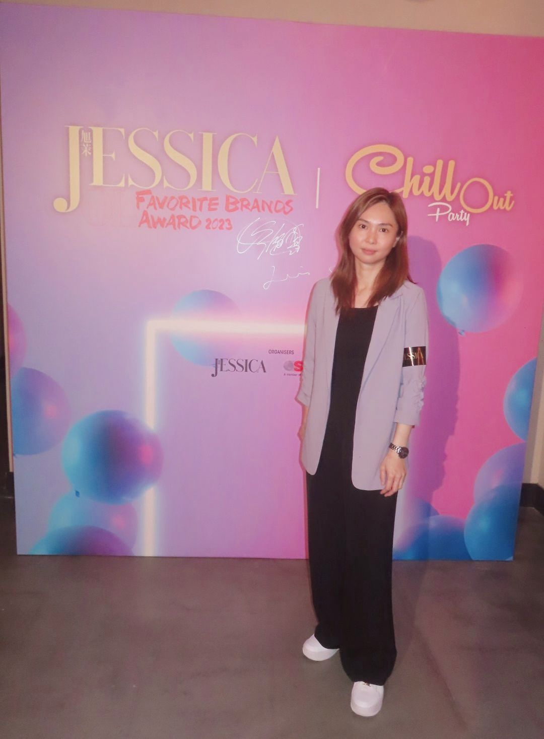 A woman is standing in front of a pink wall.