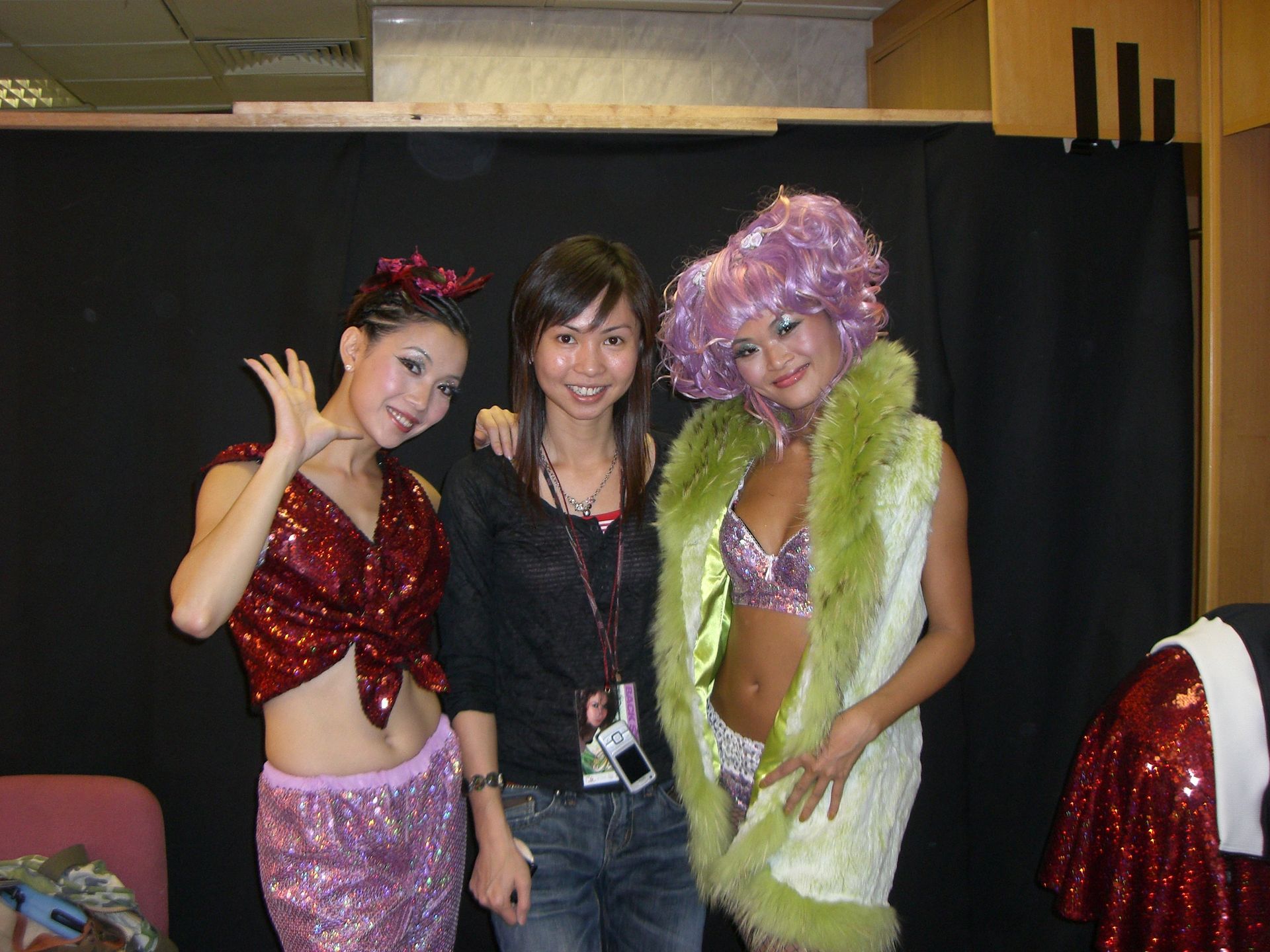 三名女性擺姿勢拍照，其中一名戴著紫色假髮