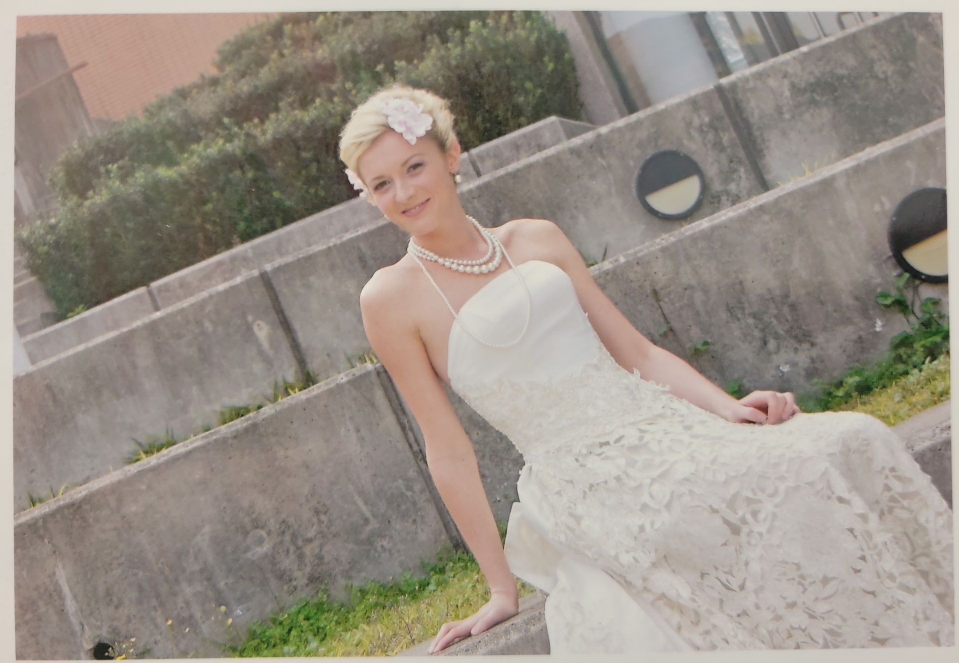 A woman in a wedding dress is sitting on a wall