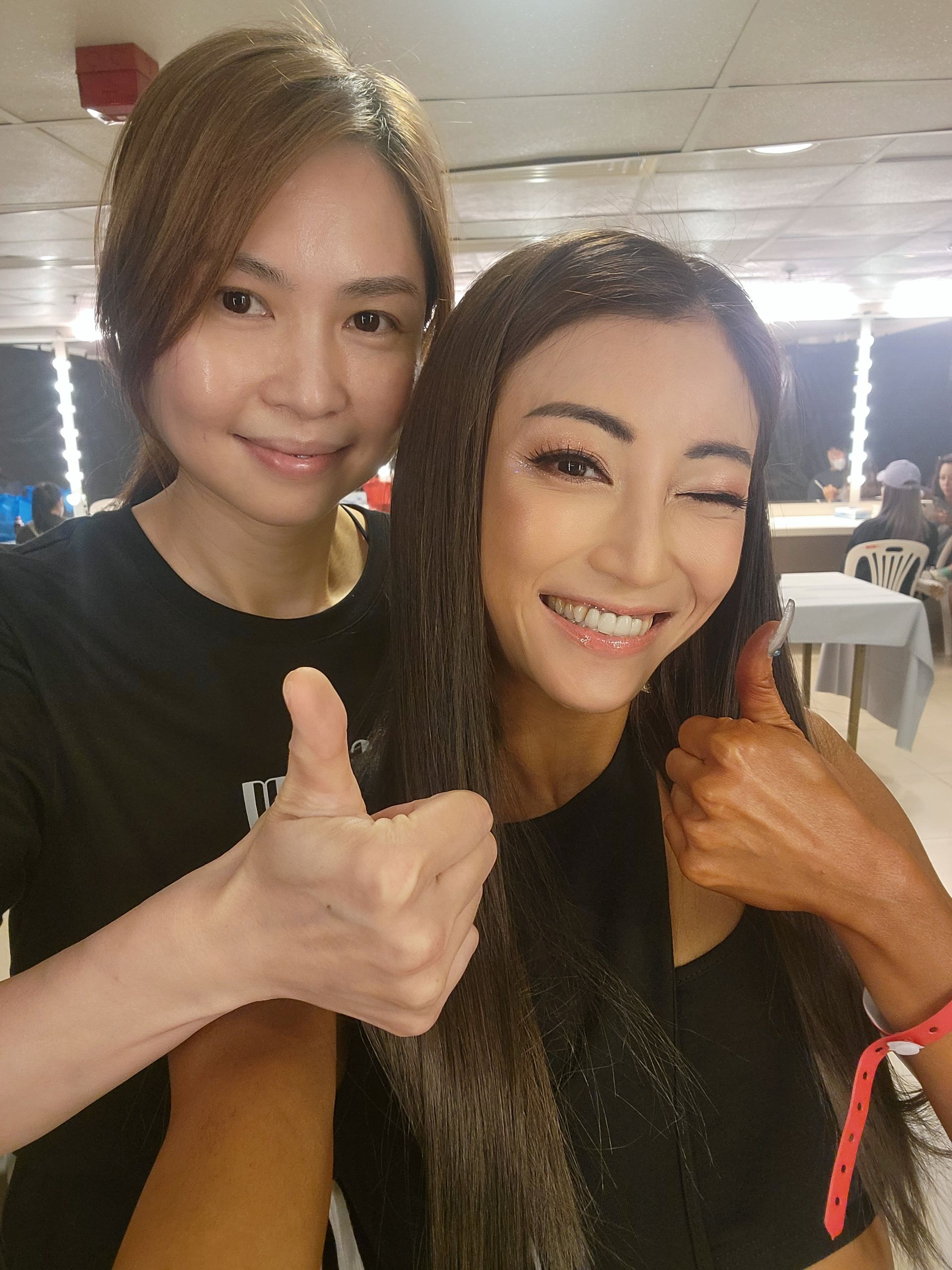 Two women are posing for a picture and one is giving a thumbs up