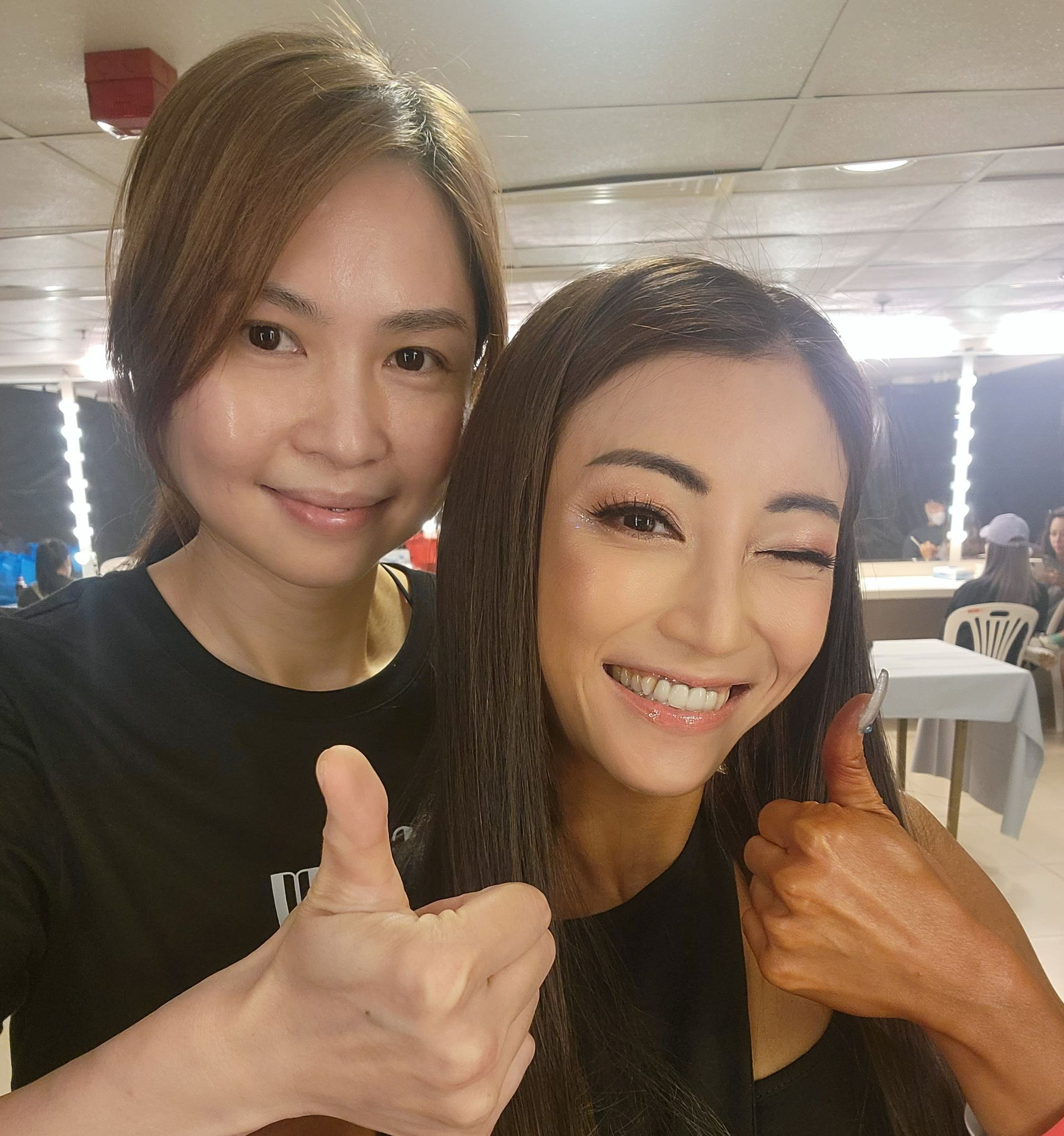 兩名女性正在擺姿勢拍照，其中一名豎起大拇指