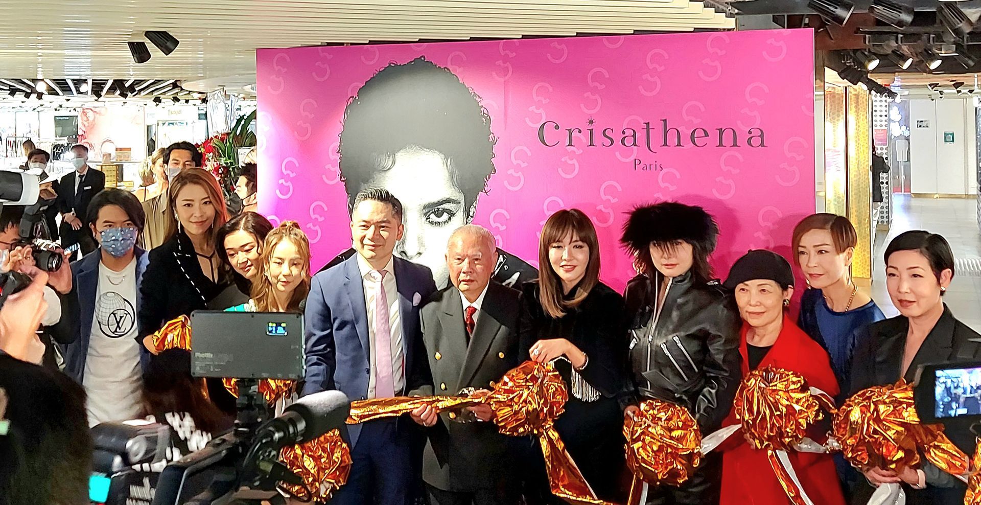 A group of people are standing in front of a pink wall.