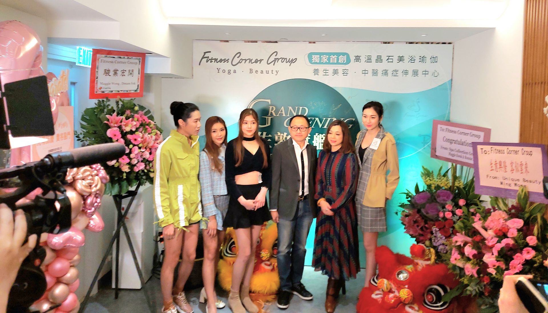 A group of people are posing for a picture in front of flowers and balloons.