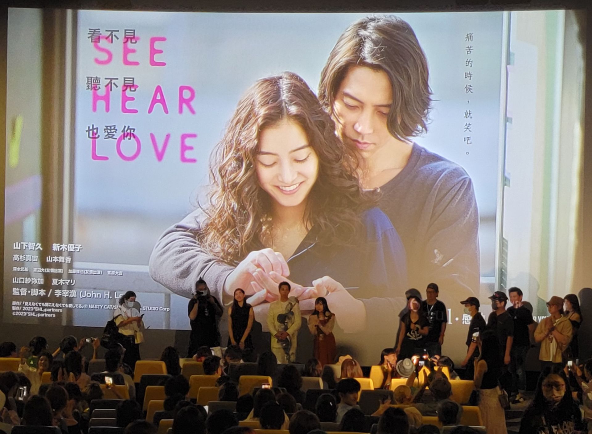 A group of people are watching a movie on a large screen.