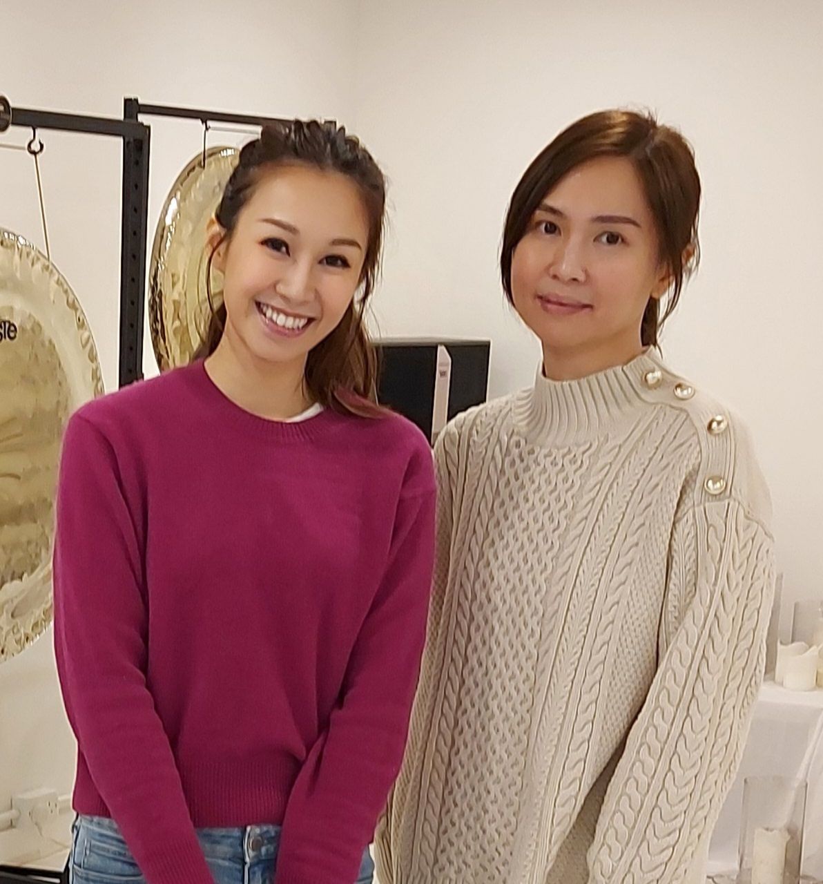 Two women standing next to each other in front of gongs