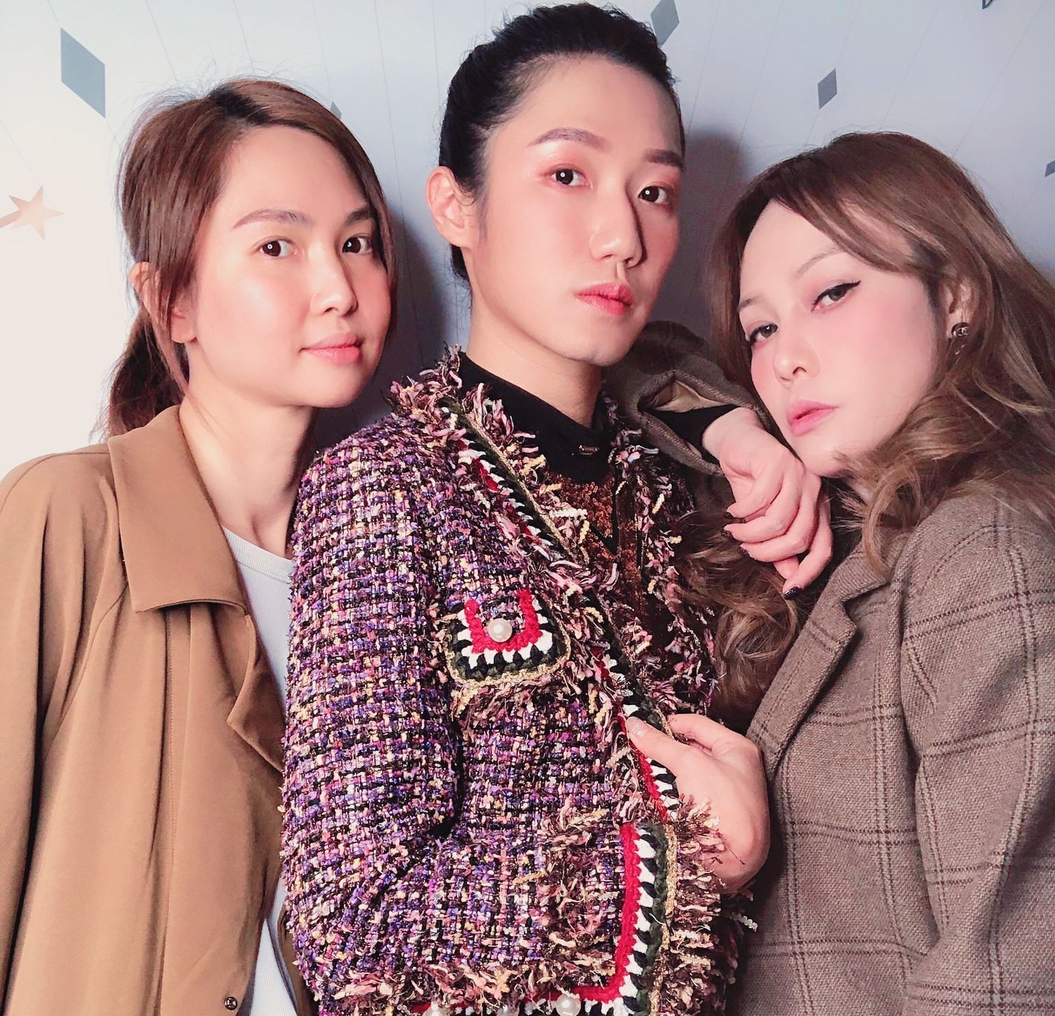 Three women posing for a picture with one wearing a purple jacket