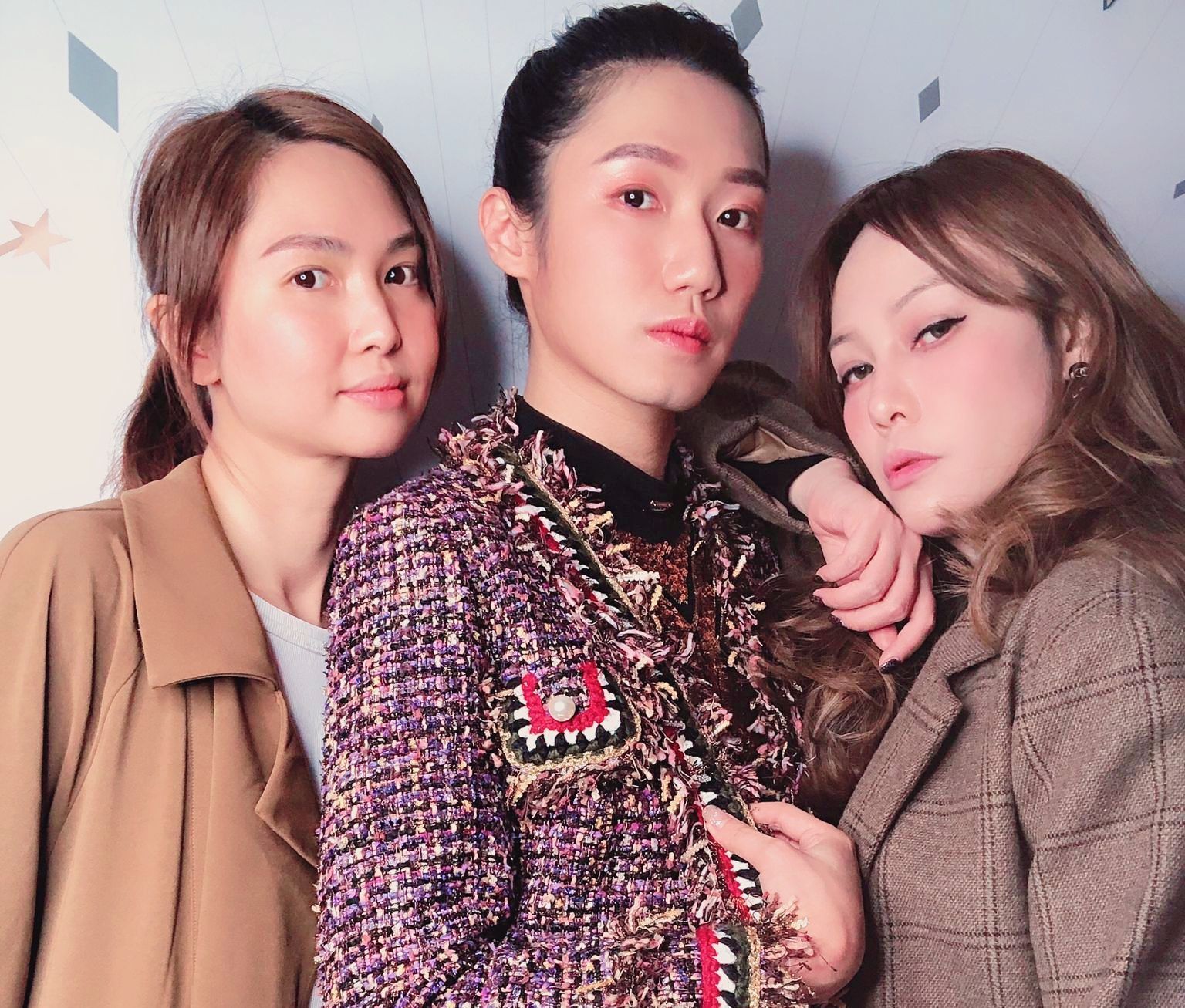 三名女子擺姿勢拍照，其中一名身穿紫色夾克