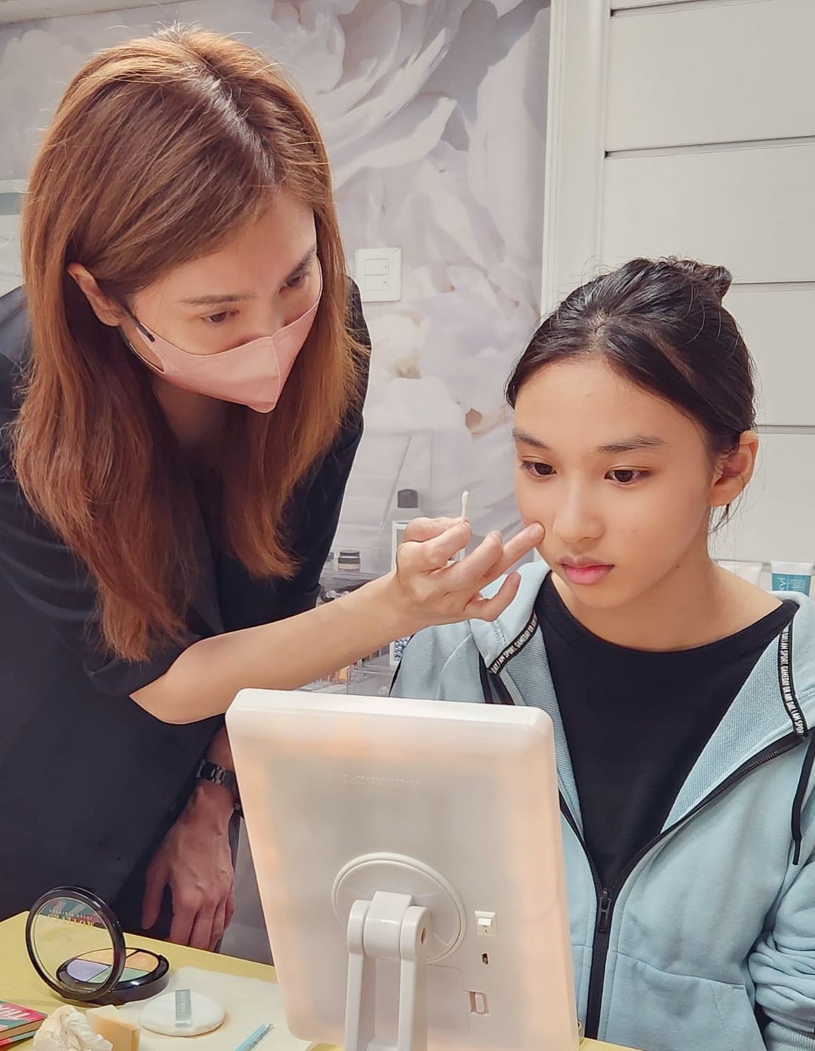 一個女人正在給一個年輕女孩的臉化妝。