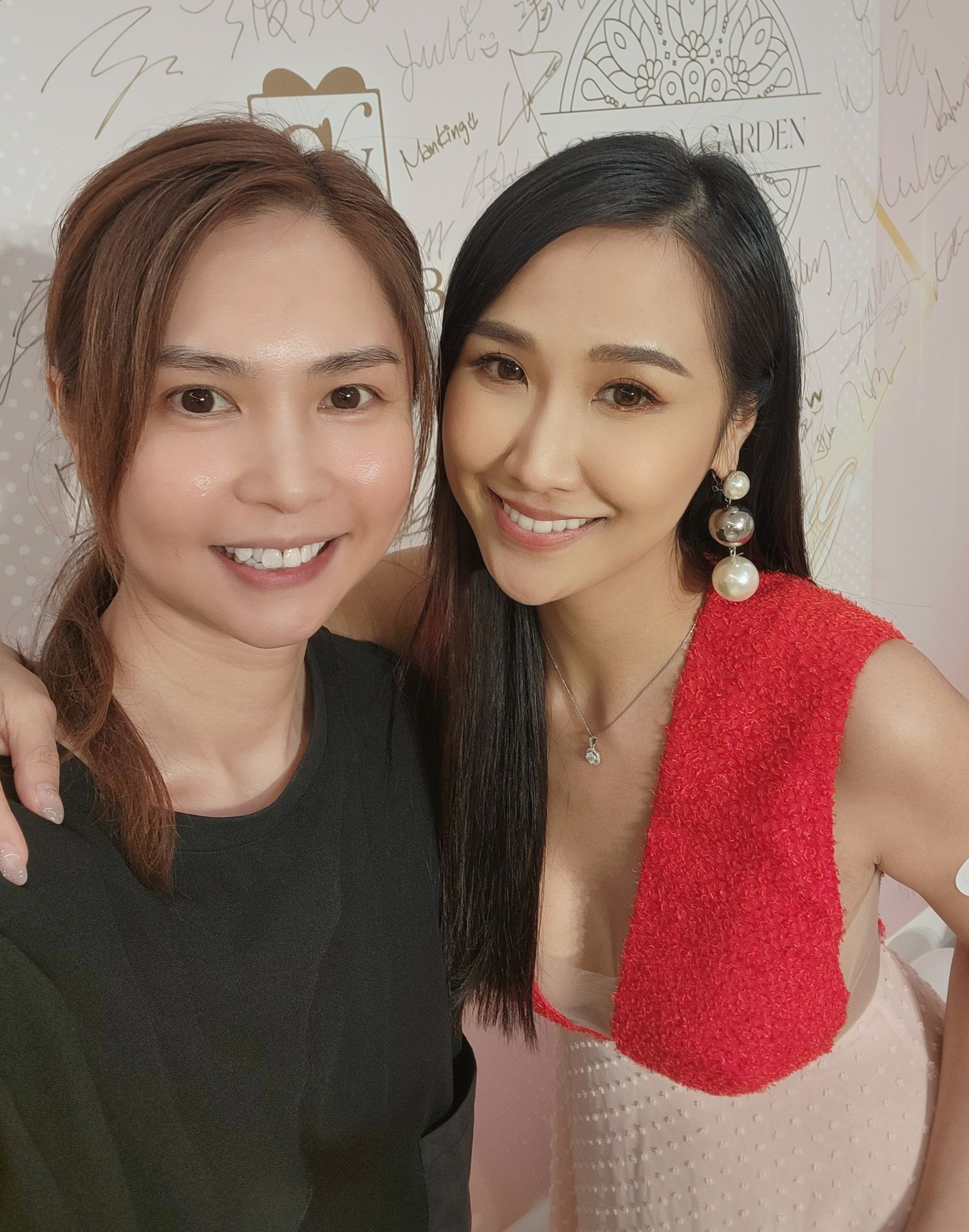 Two women are posing for a picture together and one is wearing a red dress.