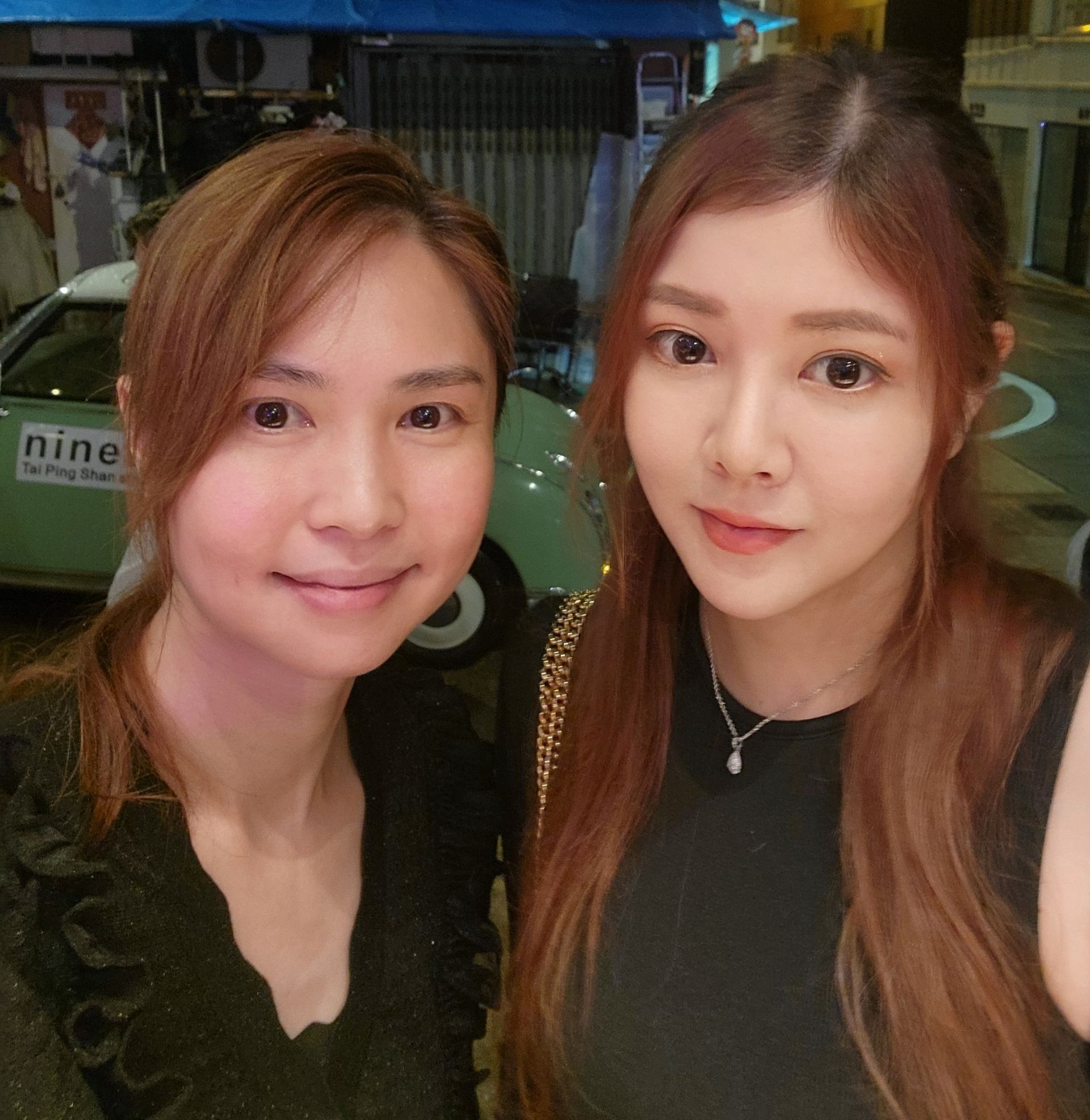 兩個女人在一輛寫著「九」的汽車前擺姿勢拍照