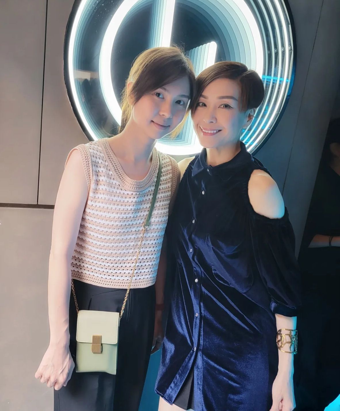 兩個女人並肩站在一塊牌子前。