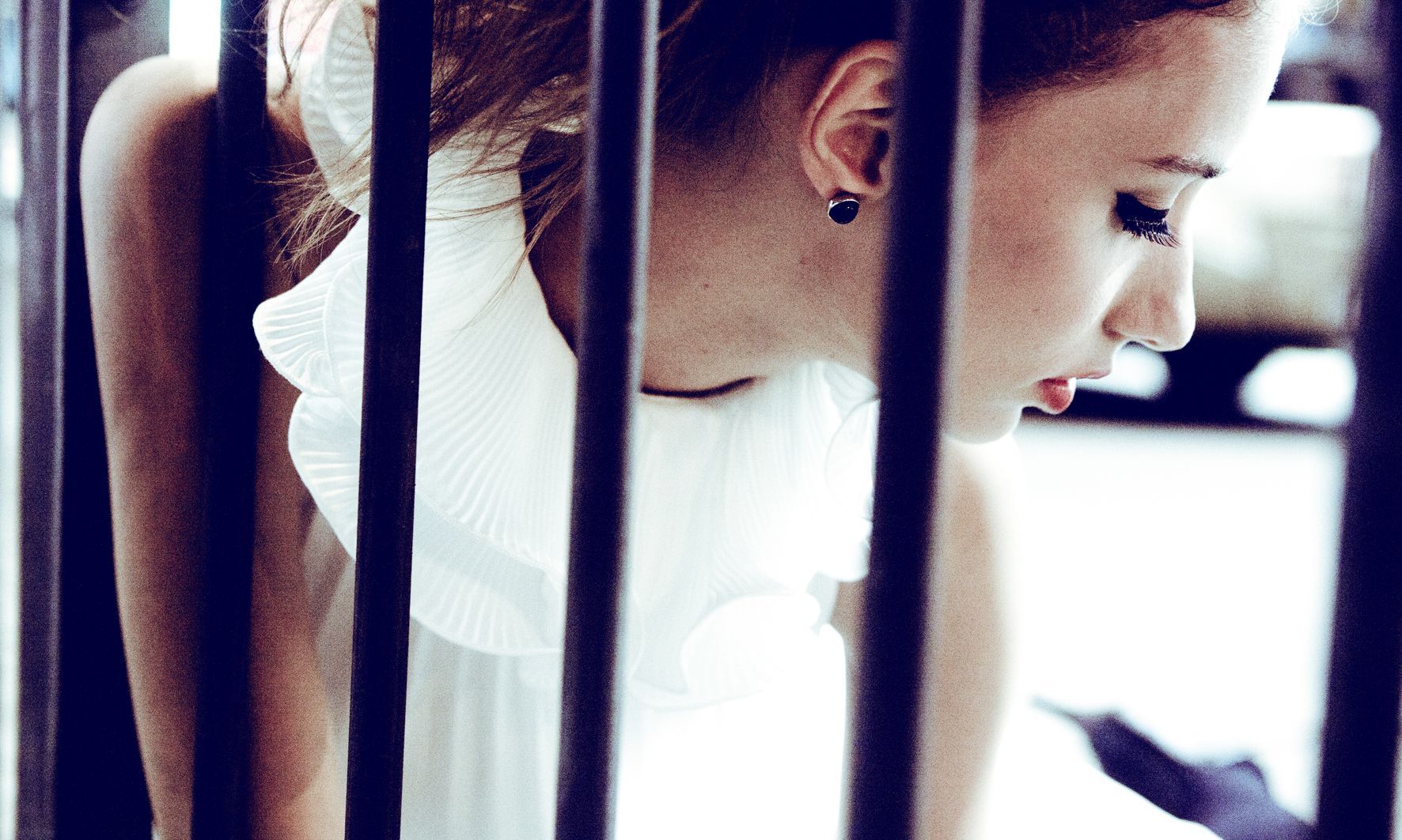 一名身穿白色洋裝的女子在監獄裡看著手機。