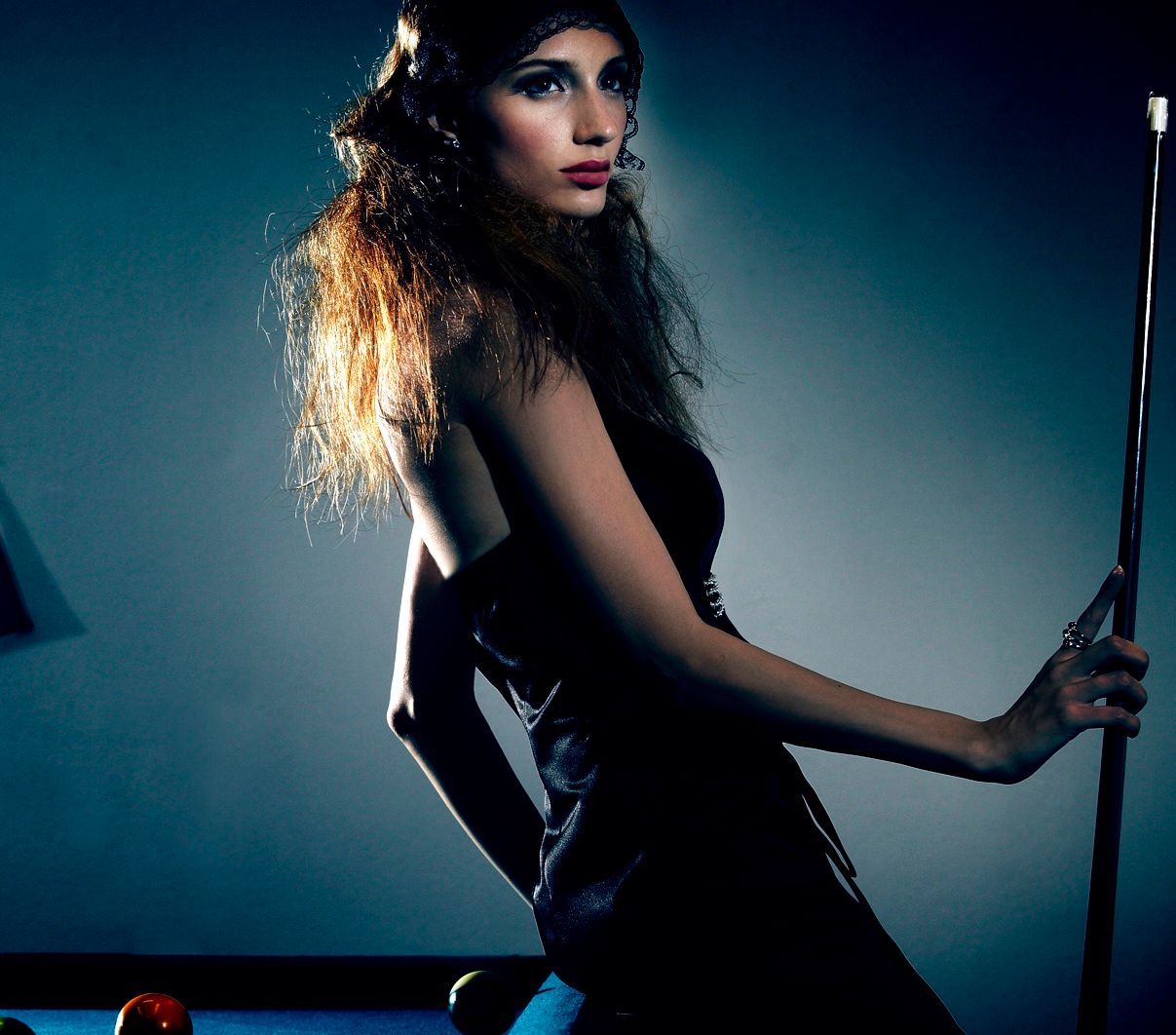 一個穿黑裙子的女人拿著撞球桿