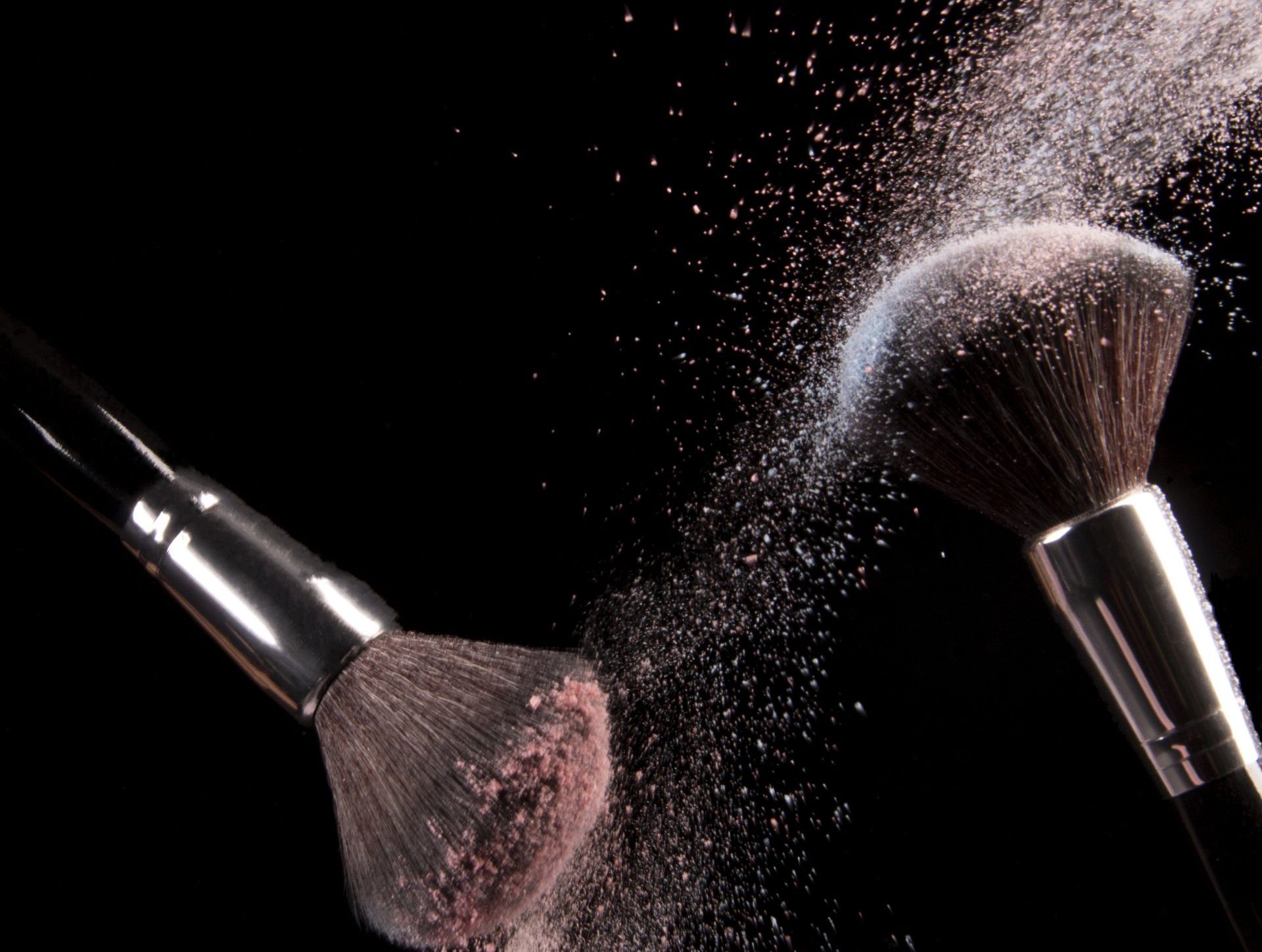 黑色背景有兩把化妝刷,上面有粉末