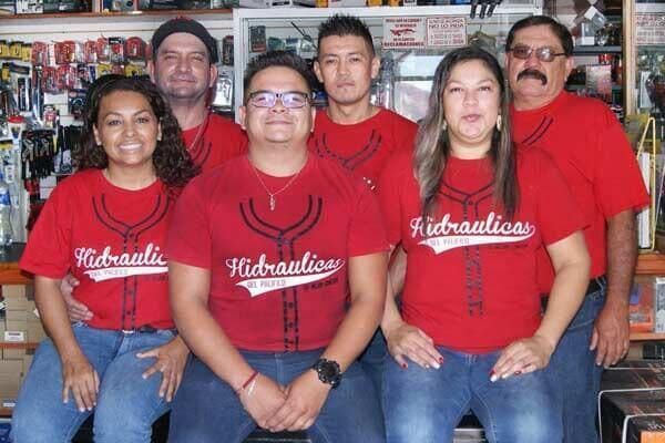 Seis personas con camisetas rojas posando en el interior detrás de un mostrador.