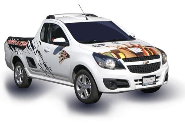 Camioneta blanca con coloridos gráficos estilo carreras sobre un fondo liso.