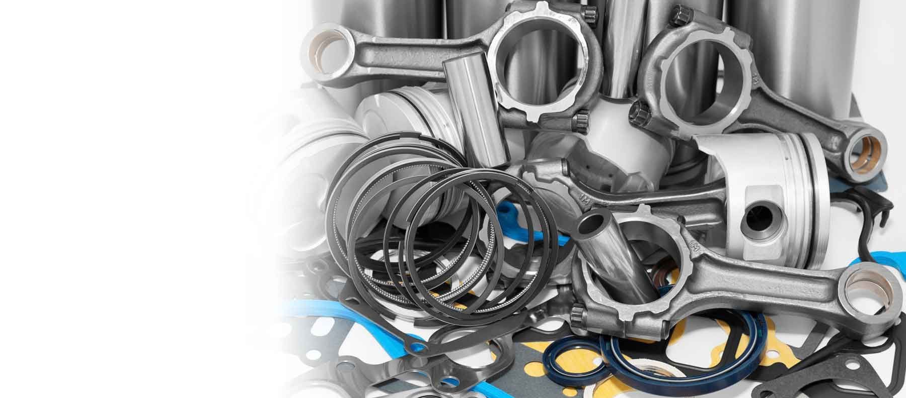 Varias piezas metálicas, arandelas y anillos apilados sobre un fondo blanco.