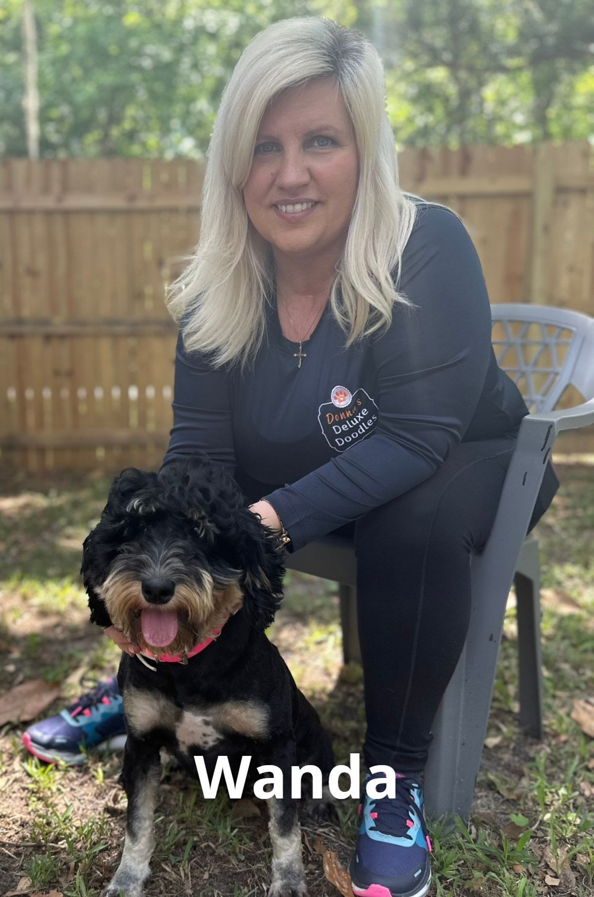 A woman is sitting on a chair next to a dog.