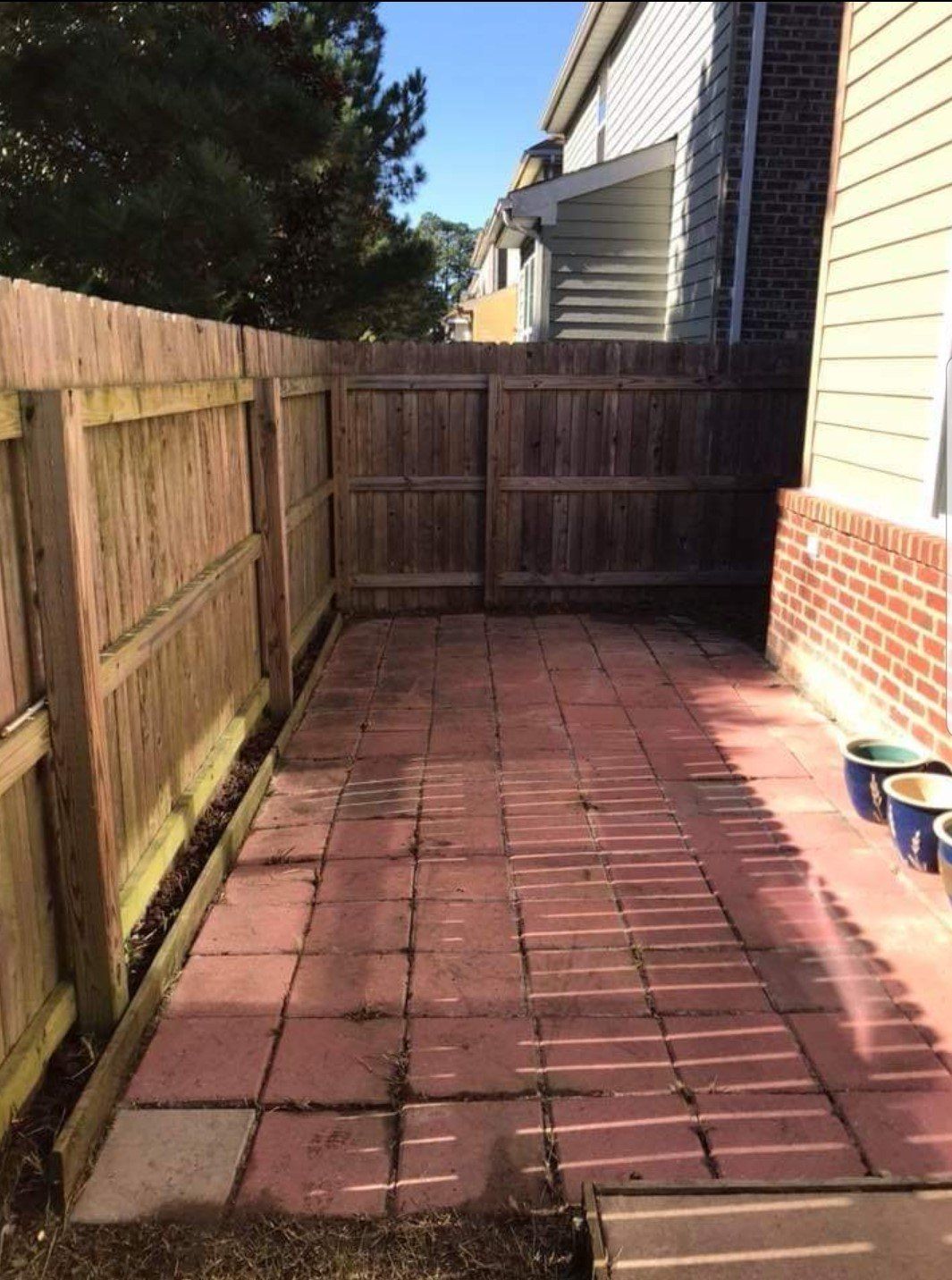A brick patio with a wooden fence surrounding it