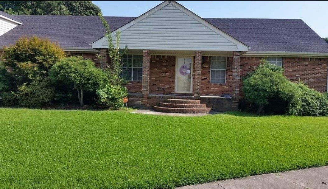 A brick house with a lush green lawn in front of it.