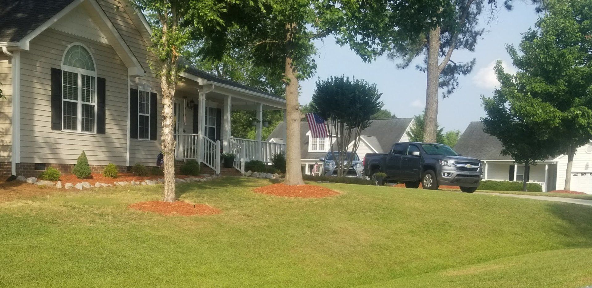 A truck is parked in front of a house with a porch.