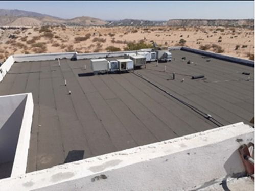 Techo plano comercial con unidades de climatización; paisaje desértico al fondo.